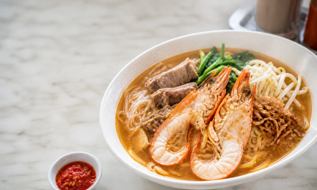 Singapore prawn mee with split tiger prawns, pork ribs, noodles, greens and chilli in a rich amber broth